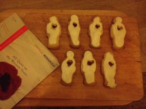 Eight biscuits in the shape of men with white icing and hearts cut out to reveal the red jam between the biscuit layers. And a book. 